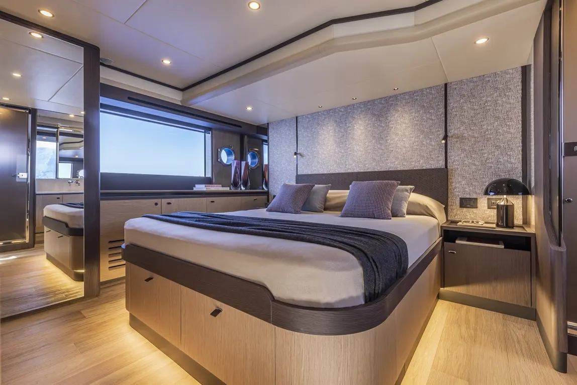 Modern yacht bedroom featuring a double bed, decorative pillows, ambient lighting, and large windows with a sea view.